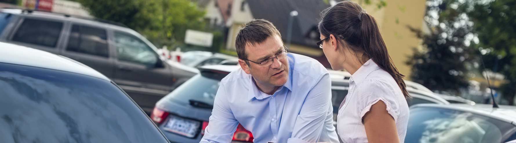 Man and woman exchanging insurance information over a car