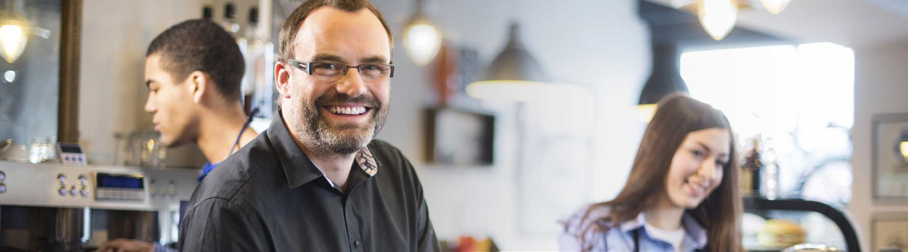 Business owner smiling behind counter of coffee shop business