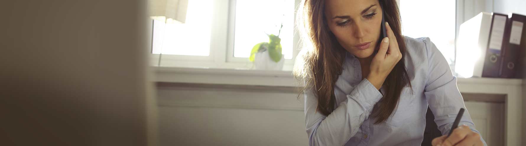 woman on phone writing something down